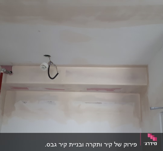 קיר גבס עם צינור אדום ותקרה חלקית